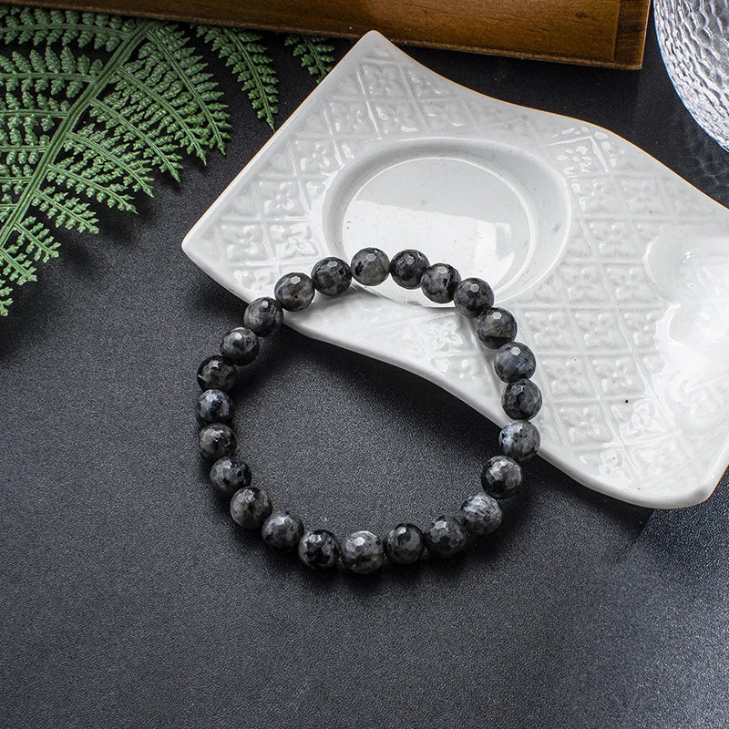 Labradorite bead bracelet shown beside a dish and fern as a close product detail.