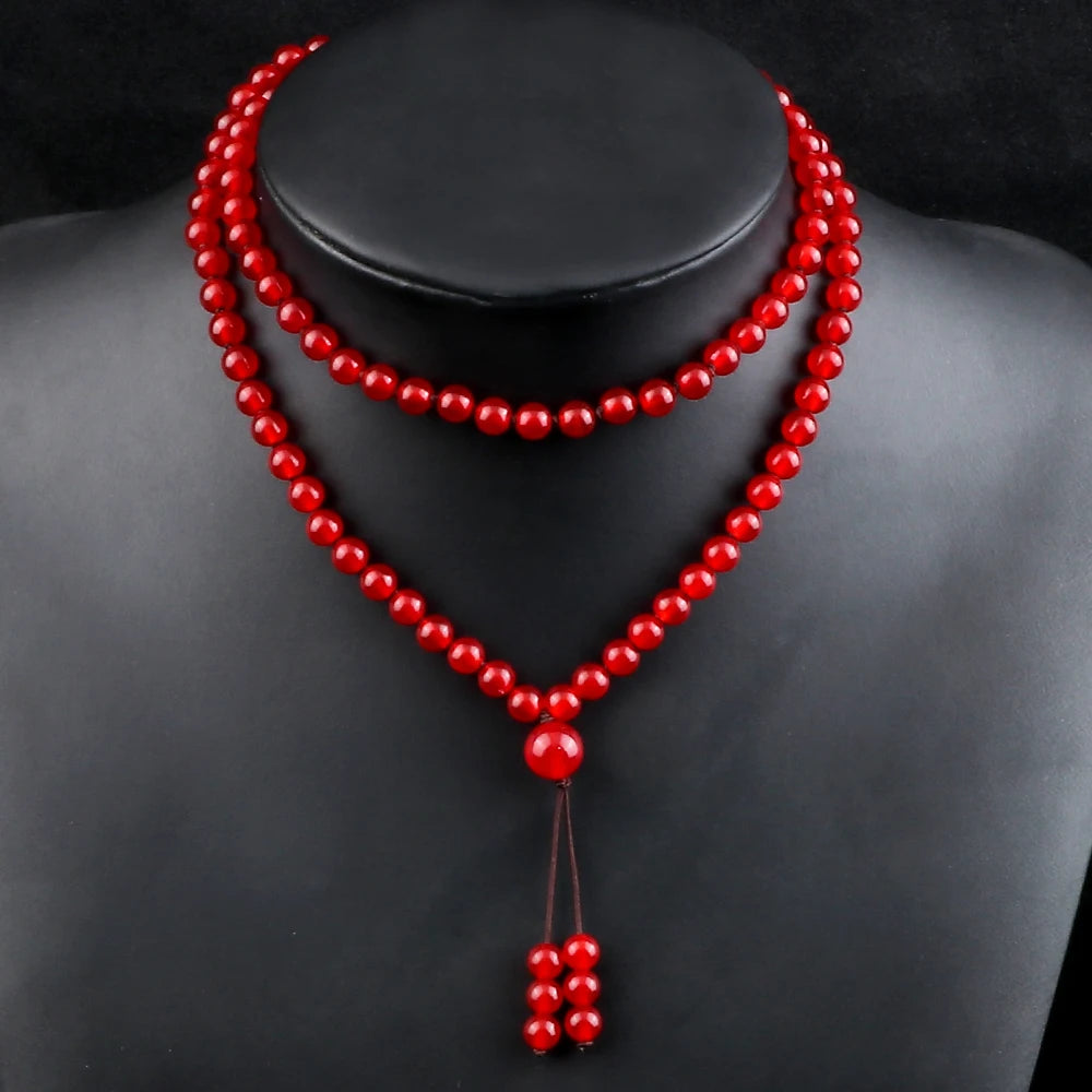 Carnelian mala worn as a long necklace on a black display bust.