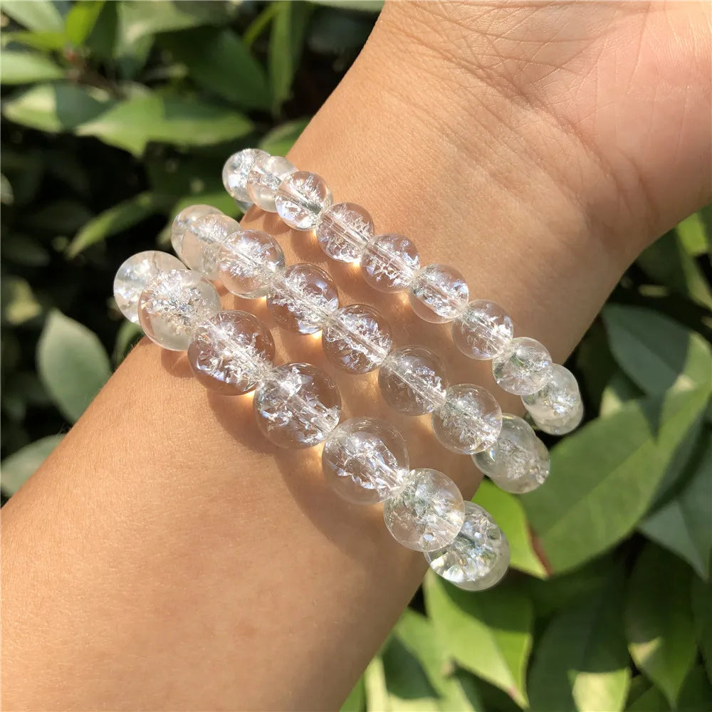 Multiple Clear Quartz bead bracelets worn together on a wrist outdoors.