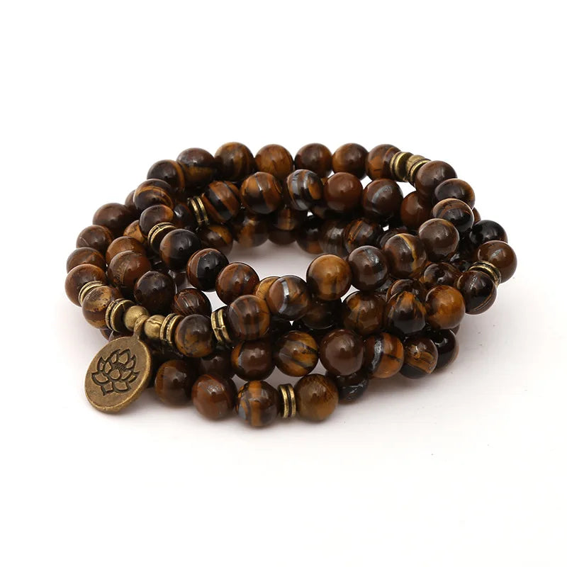 Tiger’s Eye multi-wrap mala coiled with a round lotus-style charm on a white background.