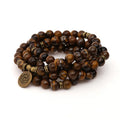 Tiger’s Eye multi-wrap mala coiled with a round lotus-style charm on a white background.