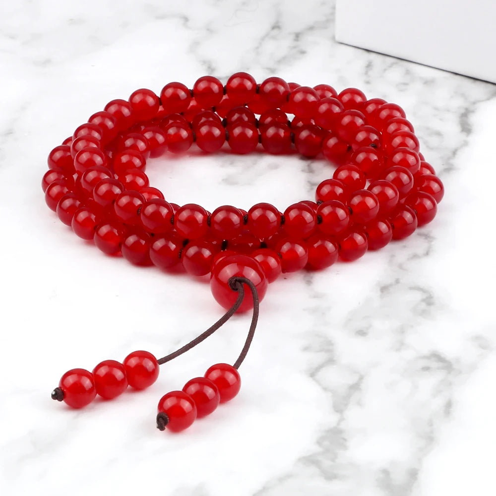 Carnelian mala coiled as a multi-wrap bracelet with knotted cord ends on marble.