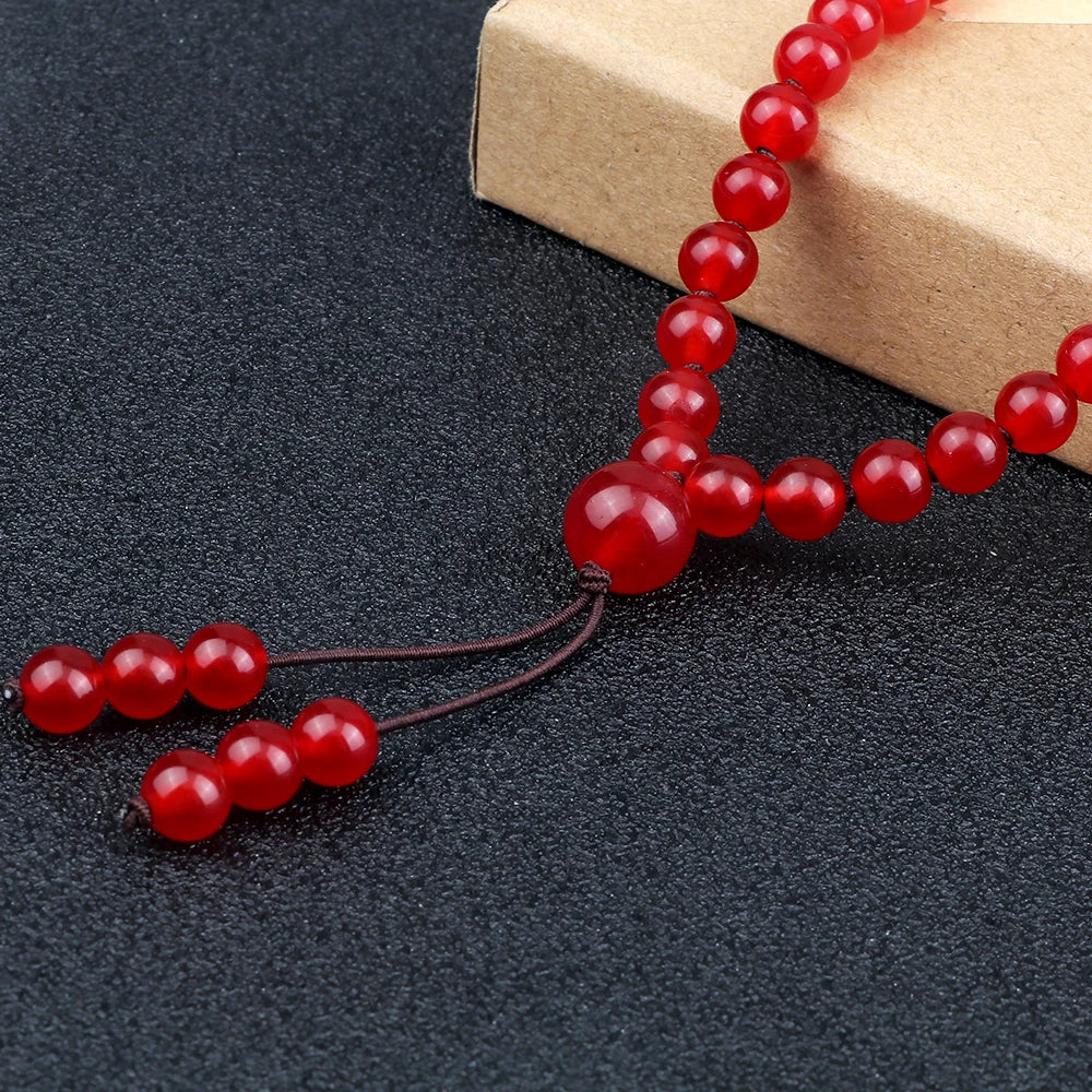Close-up of Carnelian mala beads, dark cord, and knotted end beads.