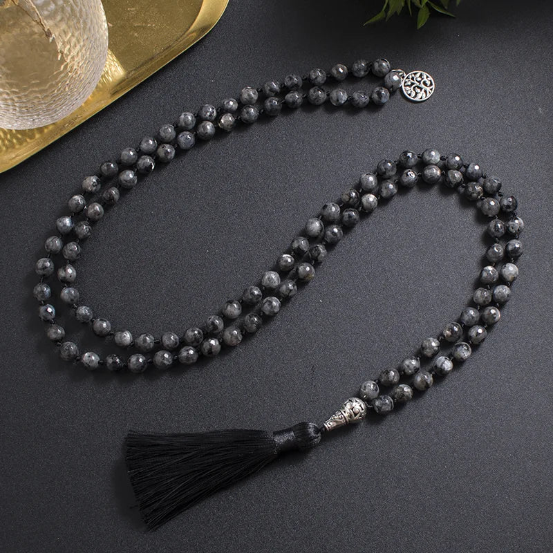 Dark Labradorite tassel mala laid in a long loop on a styled dark surface.