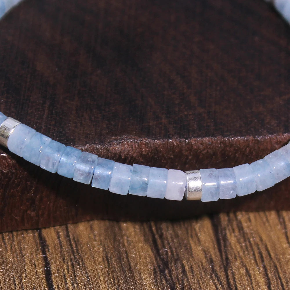 Close-up of pale blue Aquamarine rectangular beads and small metal spacers.
