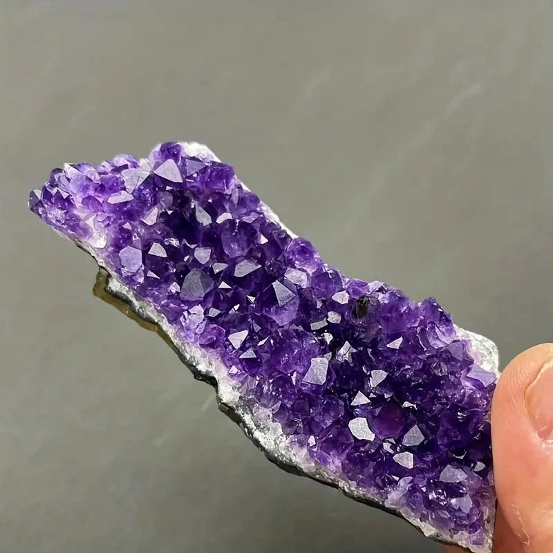 Hand-held Amethyst crystal cluster showing deep purple points and natural matrix.