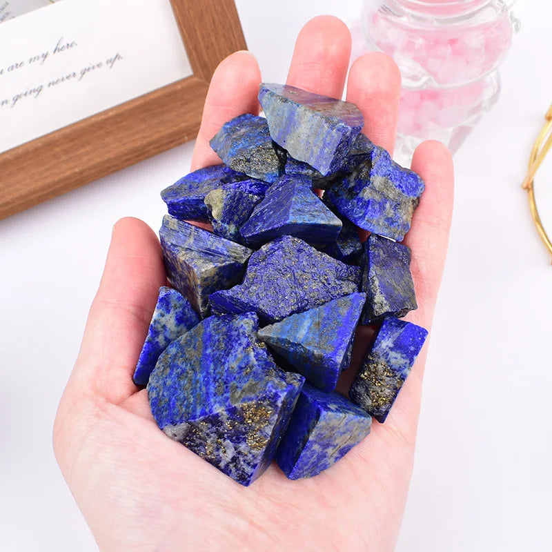 Hand holding a group of rough blue Lapis Lazuli pieces.