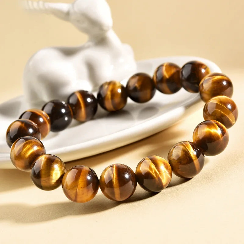 Tiger’s Eye bracelet styled beside a small sculpture on a warm neutral background.