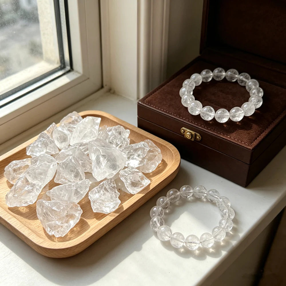 Raw Clear Quartz pieces on a wooden tray beside a Clear Quartz bracelet near a window.