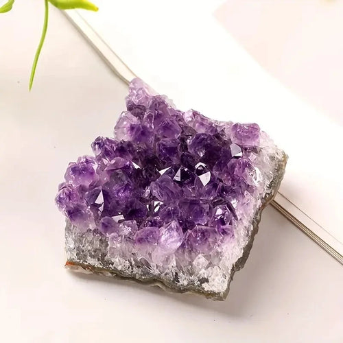Purple Amethyst crystal cluster resting beside an open book in a bright styled setting.