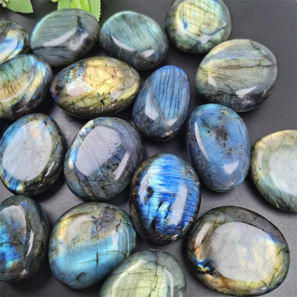 Pile of polished Labradorite tumbled stones showing varied blue, green, and gold flash.