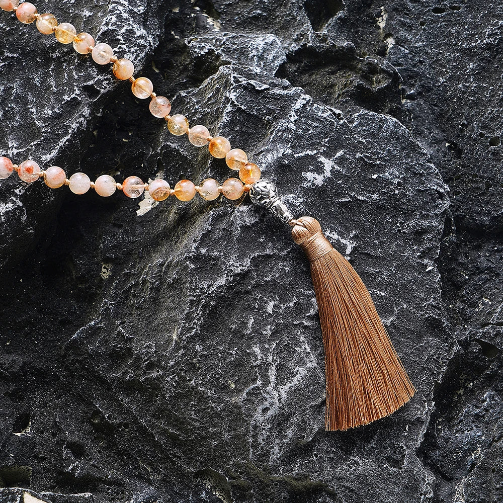 Citrine tassel mala draped over dark natural stone.