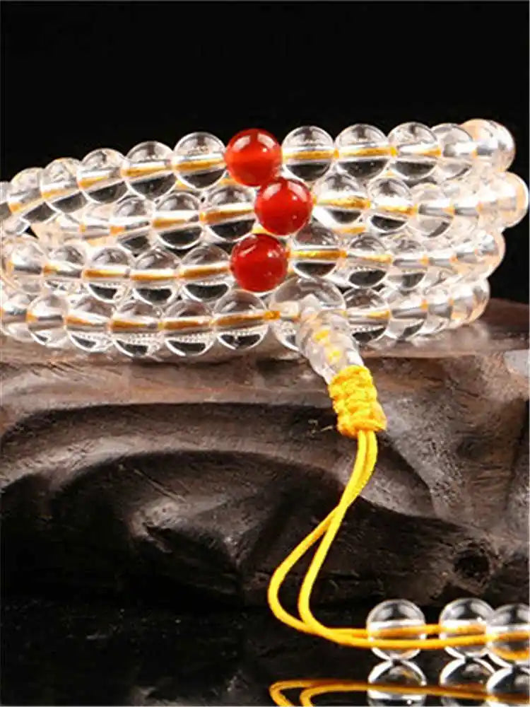 Close-up of Clear Quartz mala wrapped in loops with red accent beads and yellow cord.