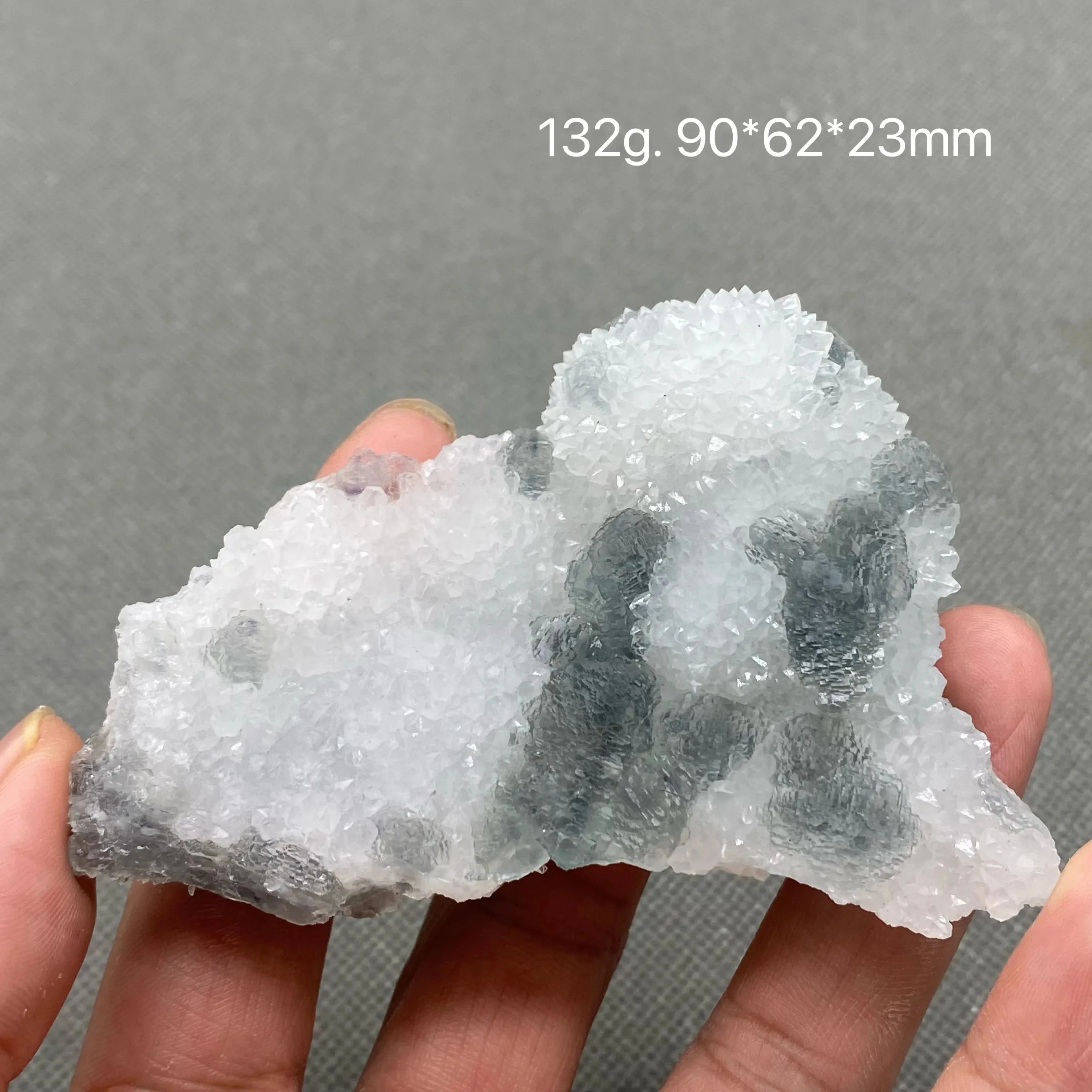 Hand holding a white crystal matrix with pale green Fluorite formations.