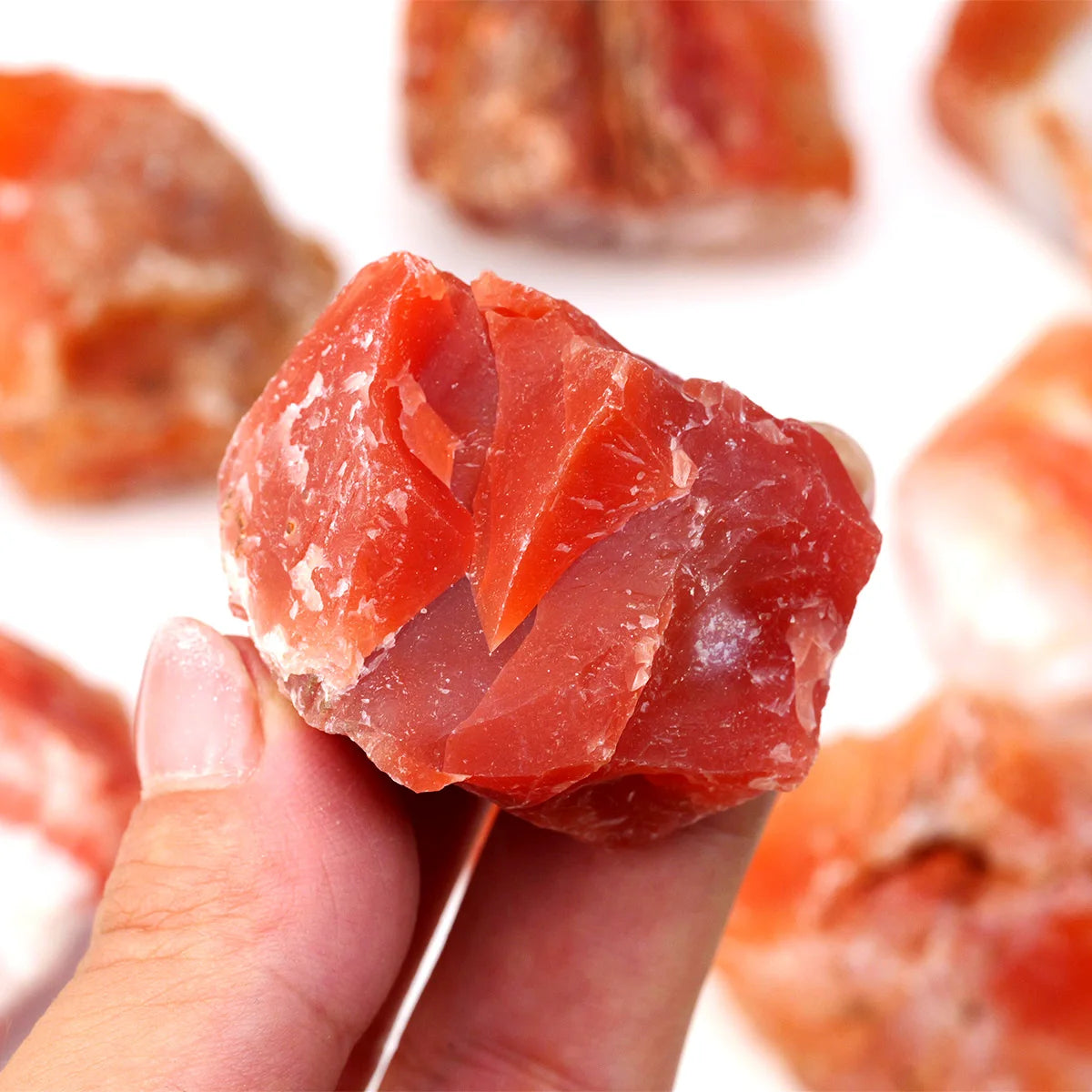 Close-up of a single rough Carnelian stone held between fingers.