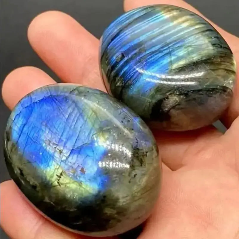 Two large polished Labradorite stones held in a hand showing vivid blue flash.