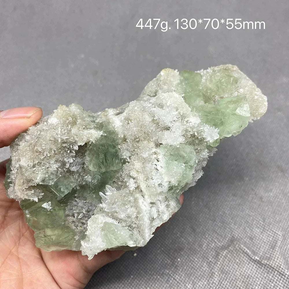 Hand holding a green and white Fluorite matrix specimen with mixed crystal growth.