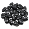 Pile of polished black Black Tourmaline tumbled stones showing varied natural shapes.