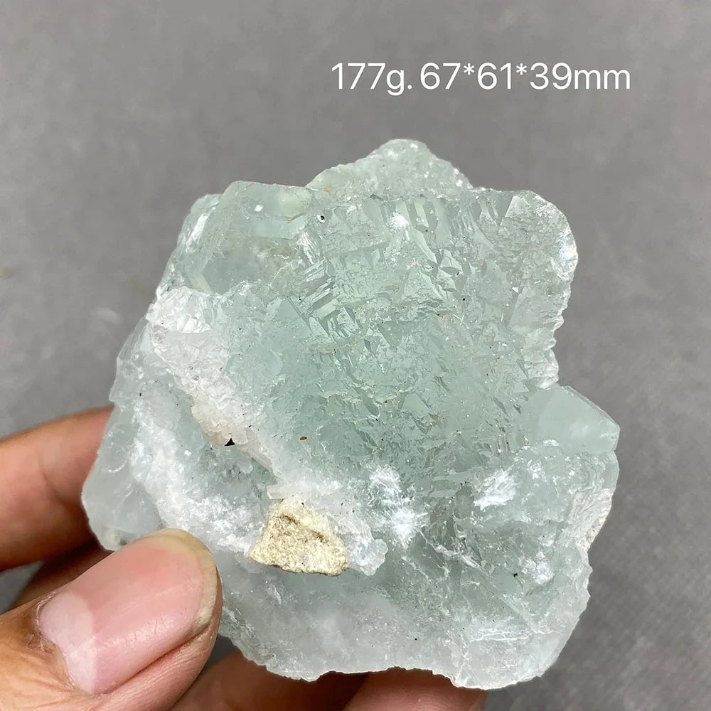 Hand holding a pale aqua-green Fluorite chunk with natural cleavage faces.