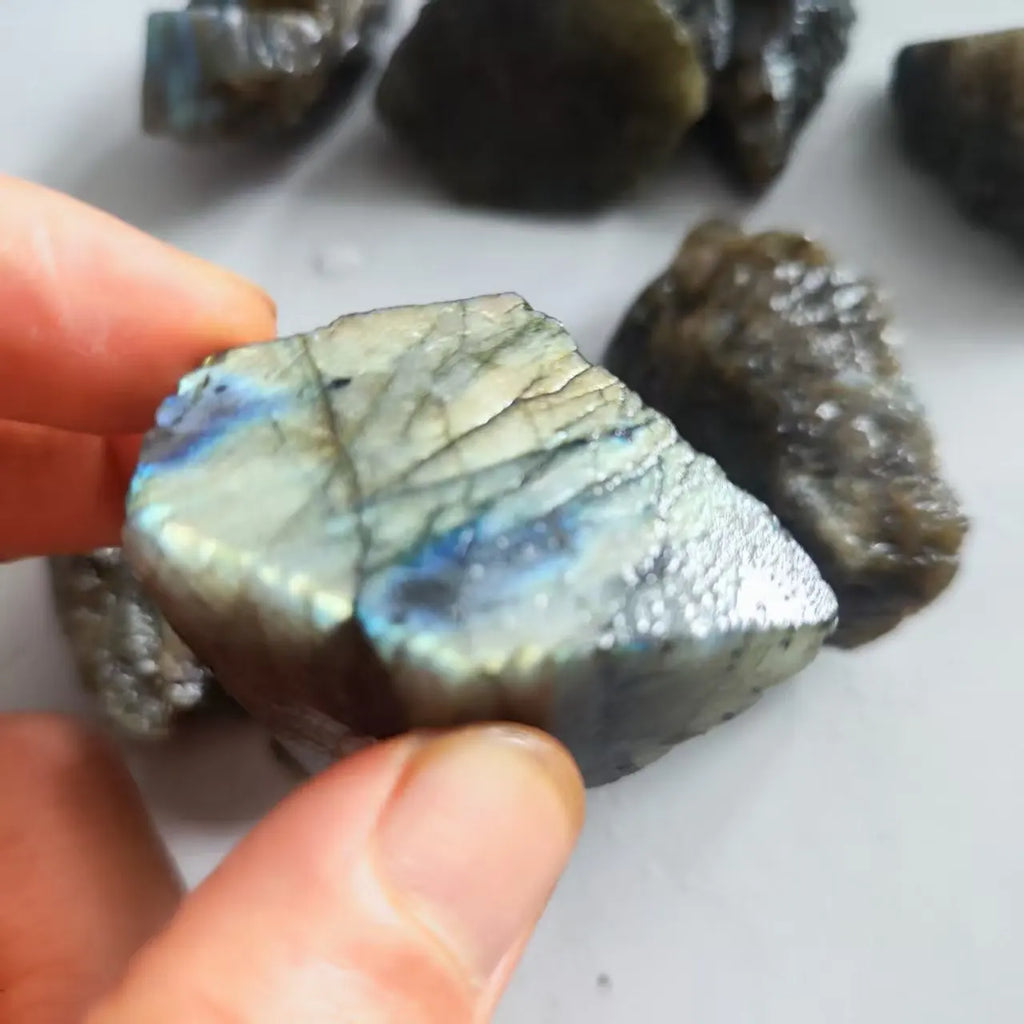 Close-up of a hand-held Labradorite piece with a strong blue-green iridescent face.