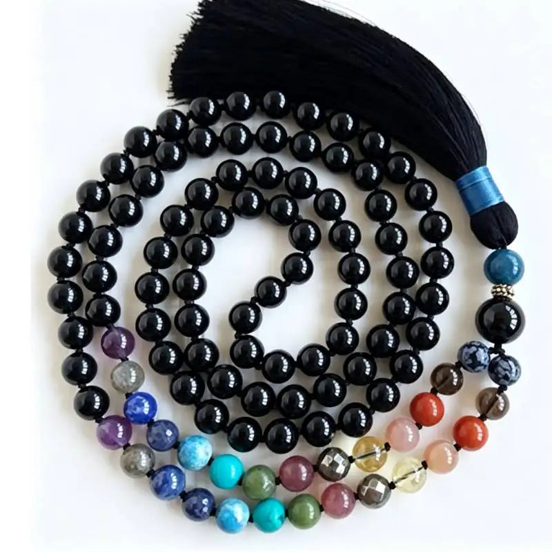 Black Tourmaline 108-bead mala coiled on white with black tassel and multicolor accent section.