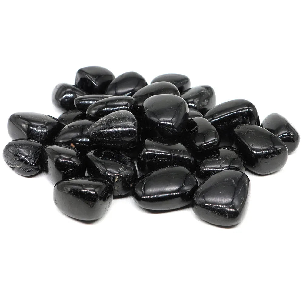 Pile of glossy Black Tourmaline tumbled stones on a white background.