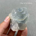 Hand holding a pale blue-gray layered Fluorite specimen with natural crystal texture.