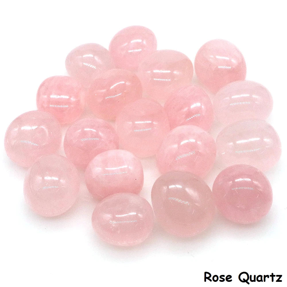 Assorted smooth pale pink Rose Quartz tumbled stones grouped on a white background.