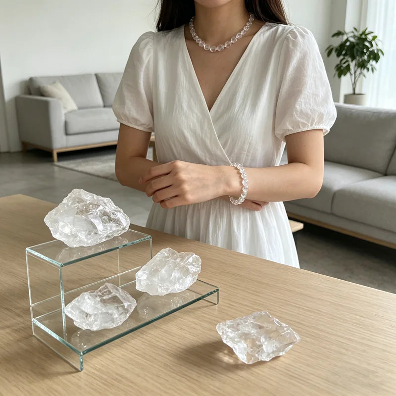 Raw Clear Quartz stones displayed on clear stands beside a person wearing crystal jewelry.