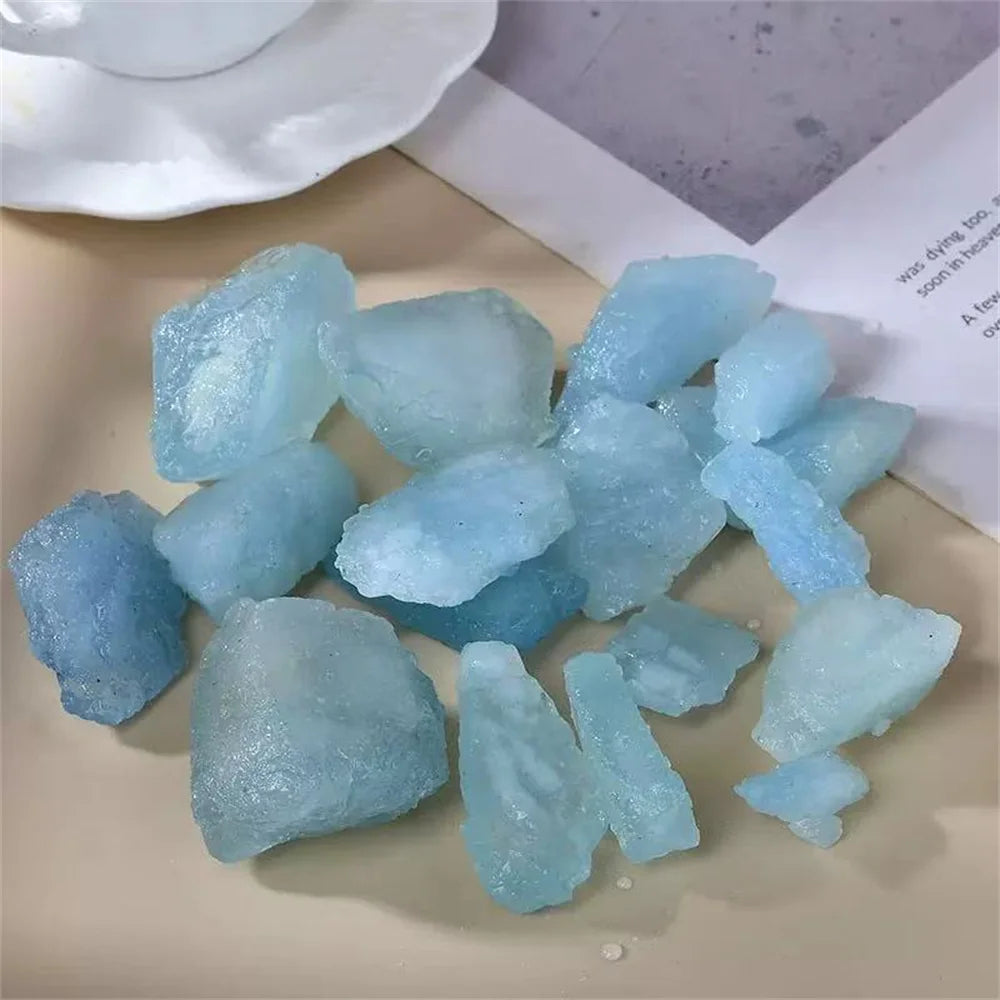 Assorted rough Aquamarine pieces arranged on a light tabletop.
