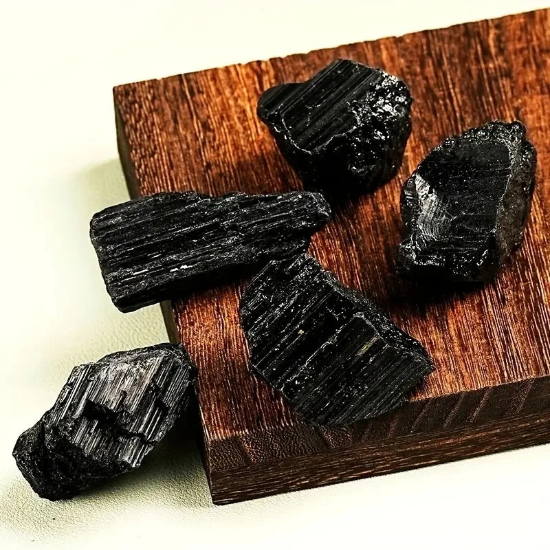 Assorted rough Black Tourmaline pieces arranged on a small wooden block.