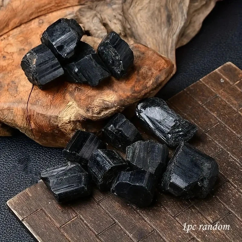 Assorted rough Black Tourmaline pieces displayed on a natural wood slice.