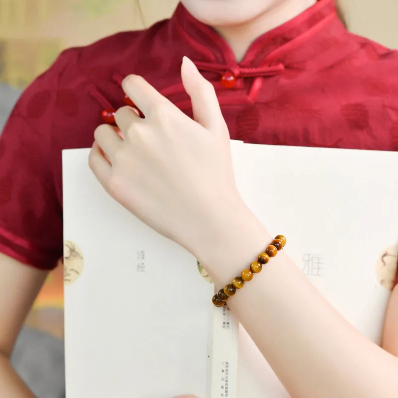 Tiger’s Eye bracelet worn on a wrist with a red garment.