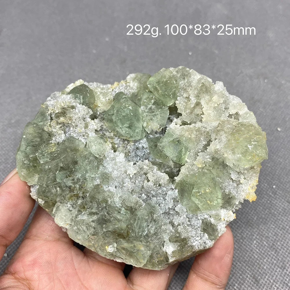 Hand holding a green Fluorite crystal cluster on pale matrix.