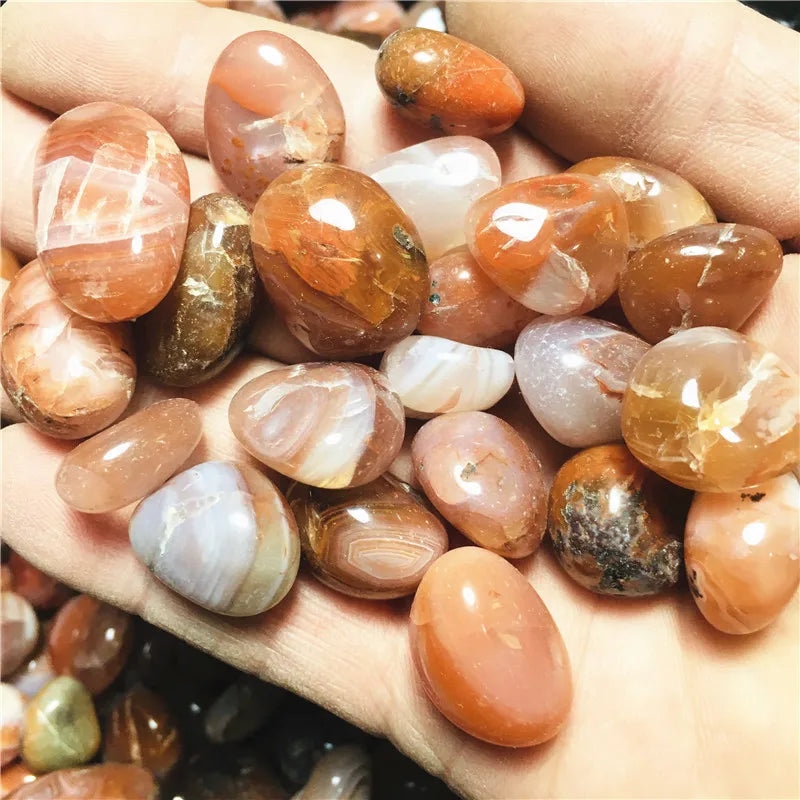 Assorted smooth Carnelian tumbled stones held in a hand, alternate view.