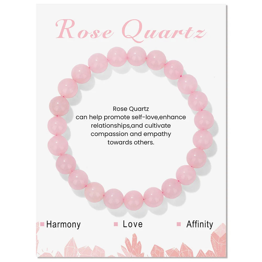 Rose Quartz round-bead bracelet displayed on a pale product card with printed crystal information.
