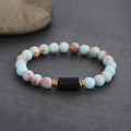 Bracelet style shown with pale multicolor beads and a black rectangular center stone.
