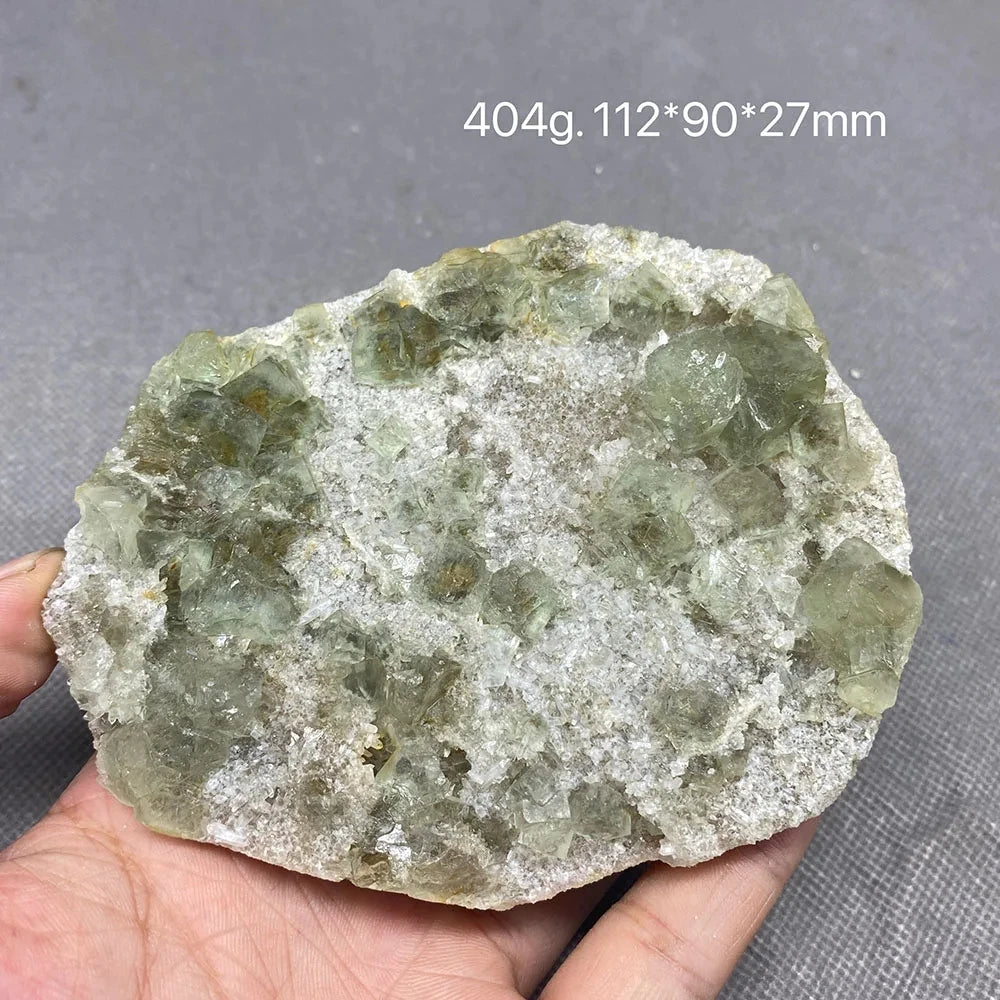 Hand holding a pale green Fluorite specimen with white druzy matrix.