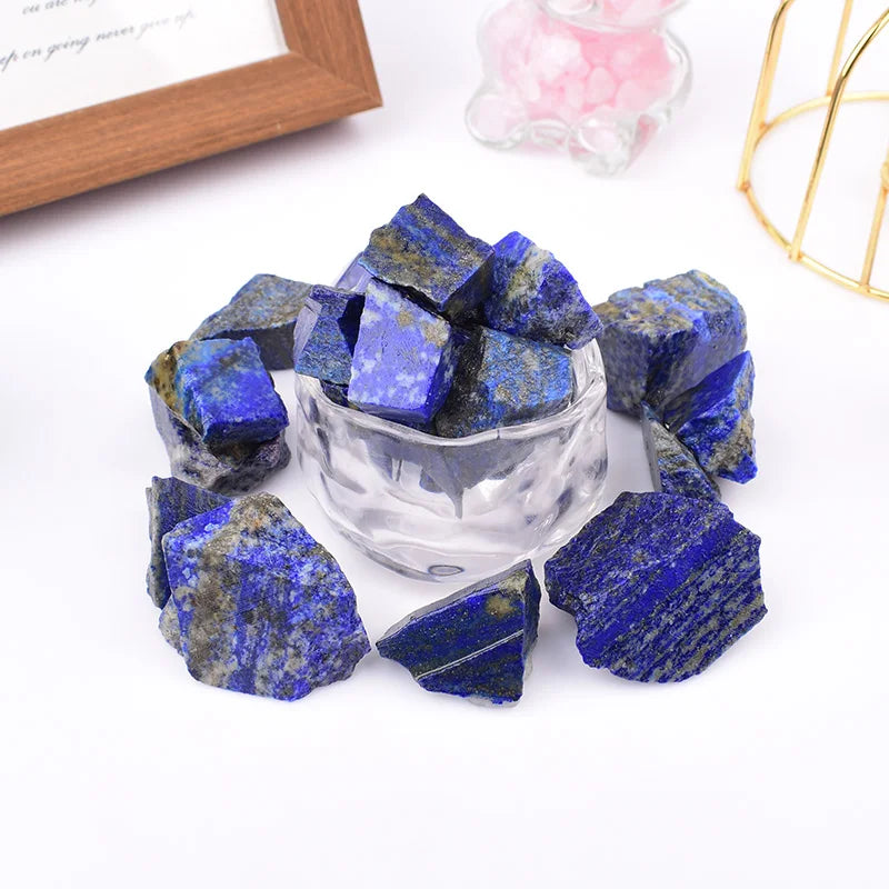 Rough Lapis Lazuli pieces arranged in and around a clear bowl in a styled setting.