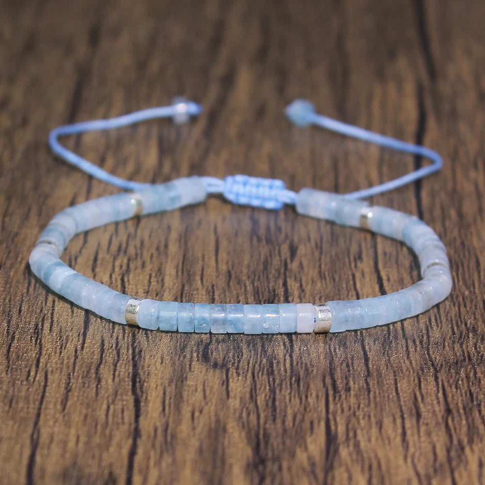 Pale blue Aquamarine rectangular-bead adjustable bracelet displayed on a wood surface.