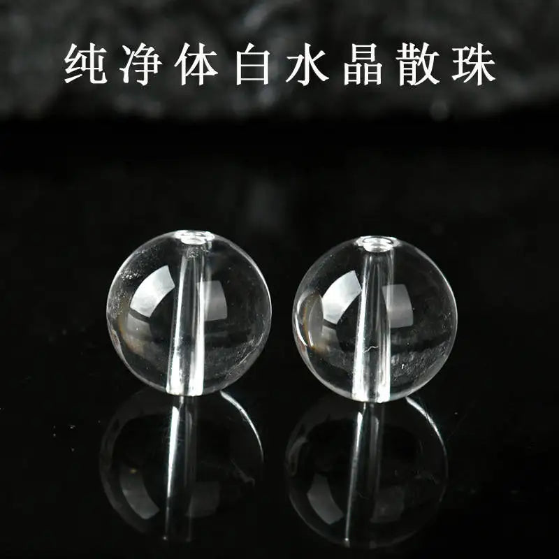 Close-up of two transparent Clear Quartz round beads on a black reflective surface.
