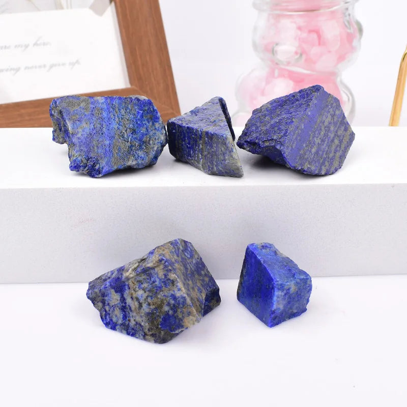 Several rough Lapis Lazuli chunks displayed on a white tiered surface.