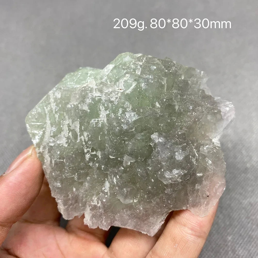 Hand holding a gray-green translucent Fluorite crystal cluster.