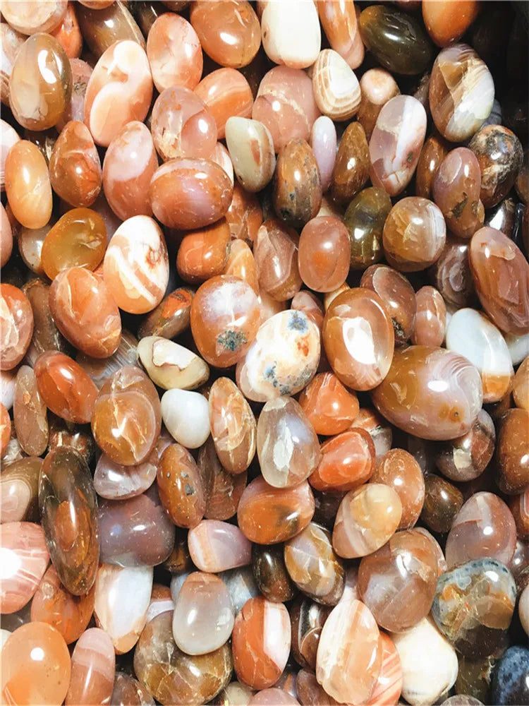 Large assortment of polished Carnelian stones showing varied natural banding and colors.