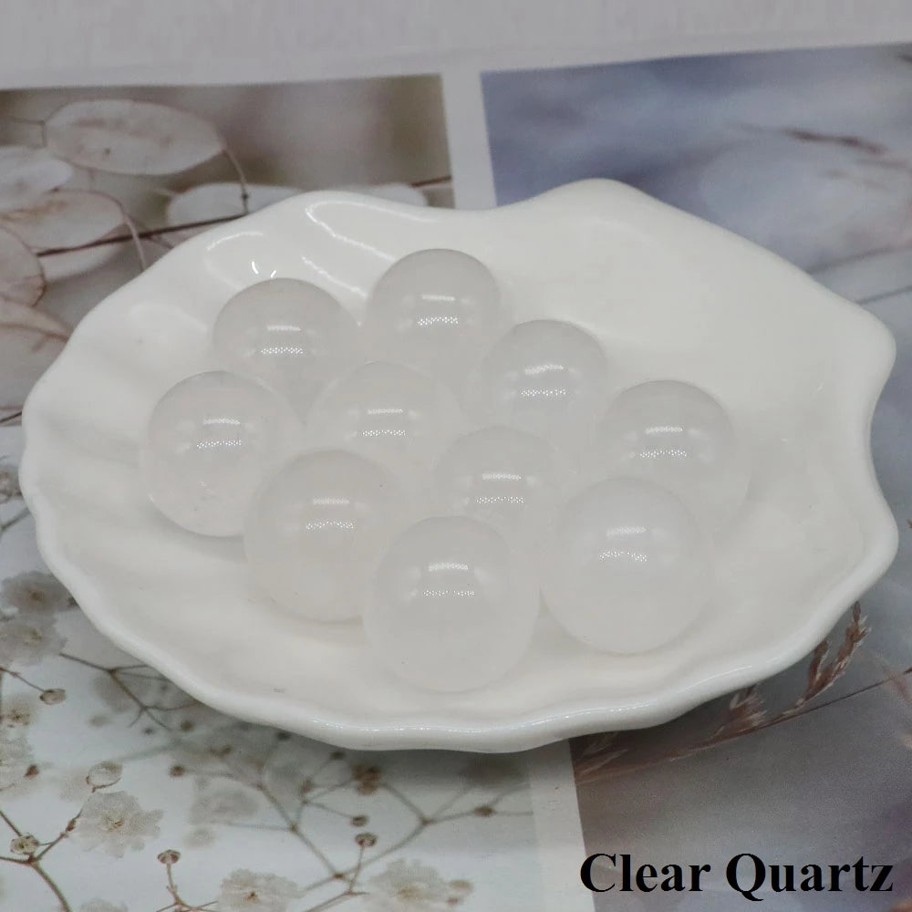 Small polished Clear Quartz pocket spheres arranged together in a white dish.