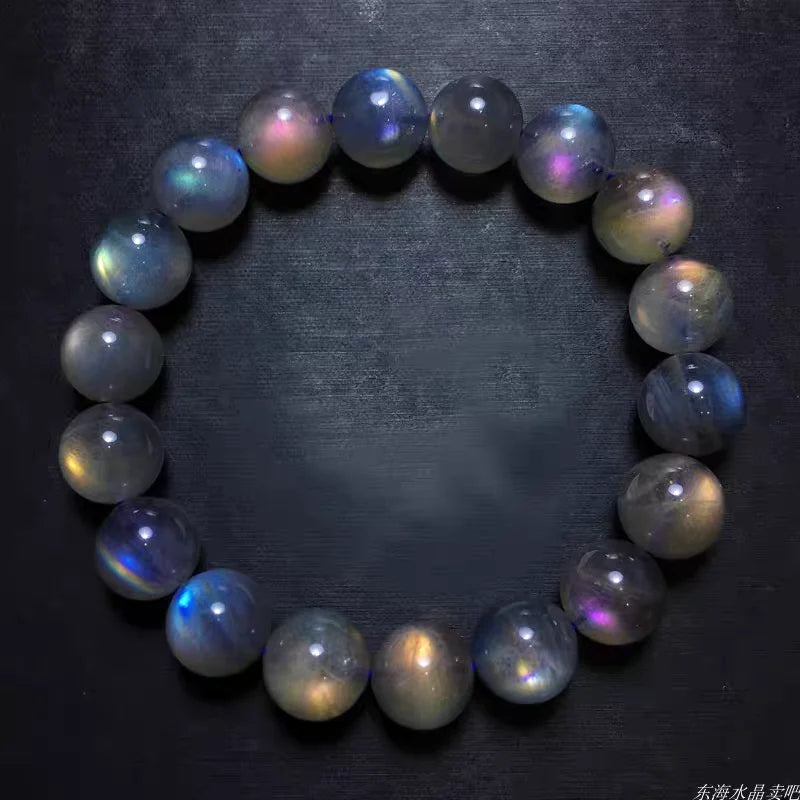 Labradorite bracelet isolated on black showing blue, gold, and purple iridescent flashes.