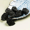 Assorted striated Black Tourmaline crystals arranged on a small decorative plate.