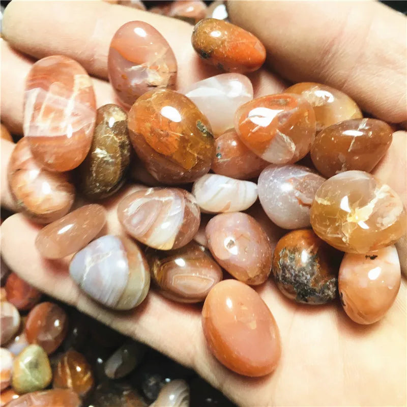 Hand holding mixed polished Carnelian tumbled stones, close alternate view.