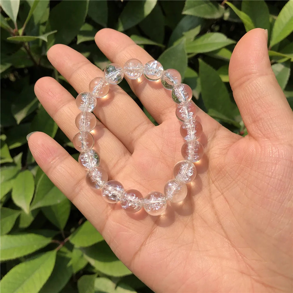 Clear Quartz bracelet held in a palm showing transparent beads and natural inclusions.