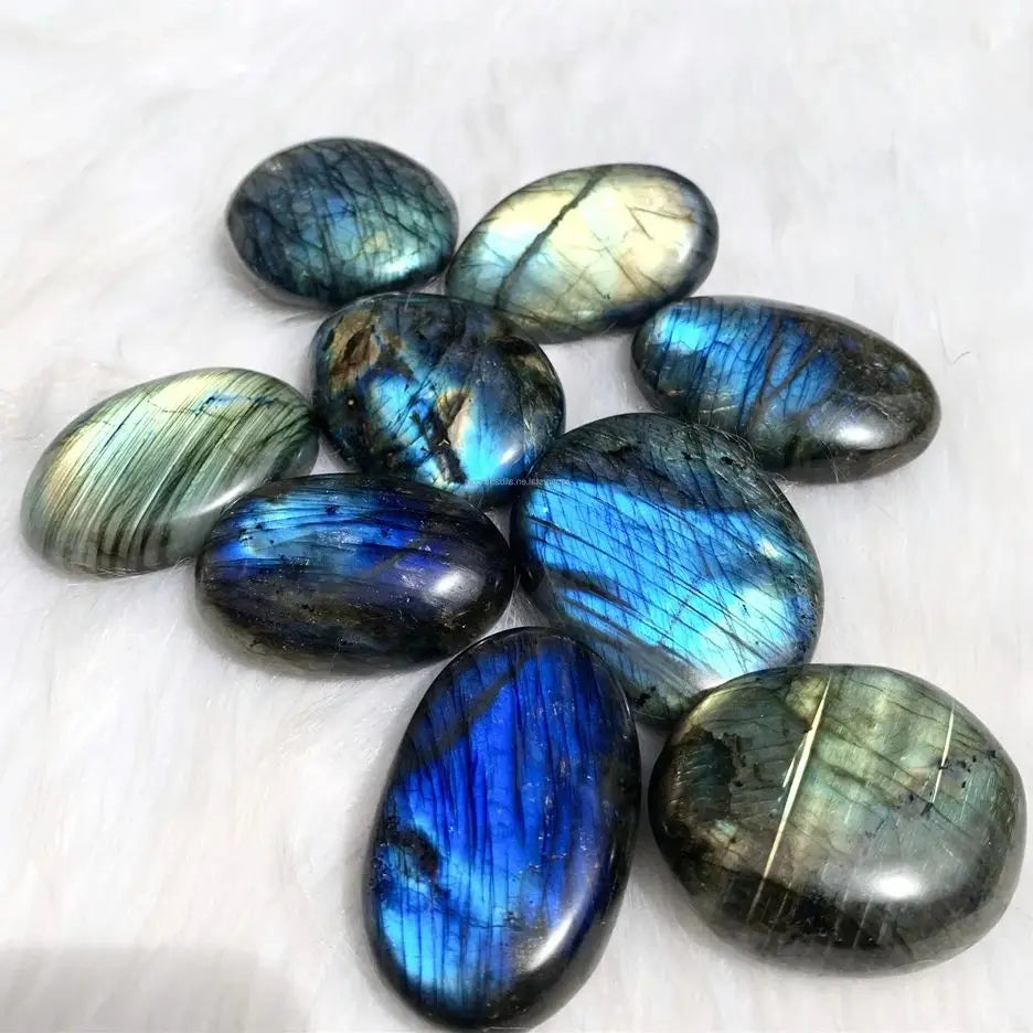Polished Labradorite stones arranged on a soft white surface with bright blue flash.